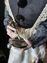 Load image into Gallery viewer, Close-up of Madame Tinker holding a clock mechanism and tool